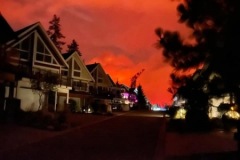 Orange, glowing smoke in background. Homes in foreground.