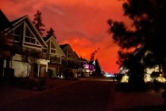 Orange, glowing smoke in background. Homes in foreground.